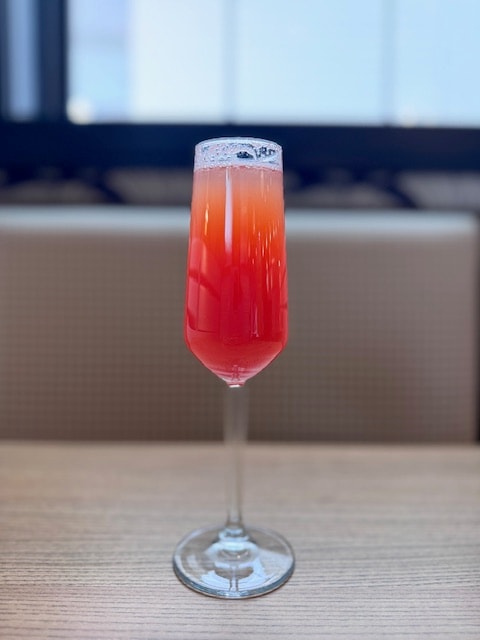Red cocktail with foam in champagne flute